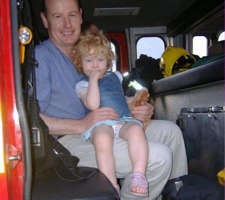 Richard Taylor,a member of the Event Team, and his young daughter resting in the fire engine